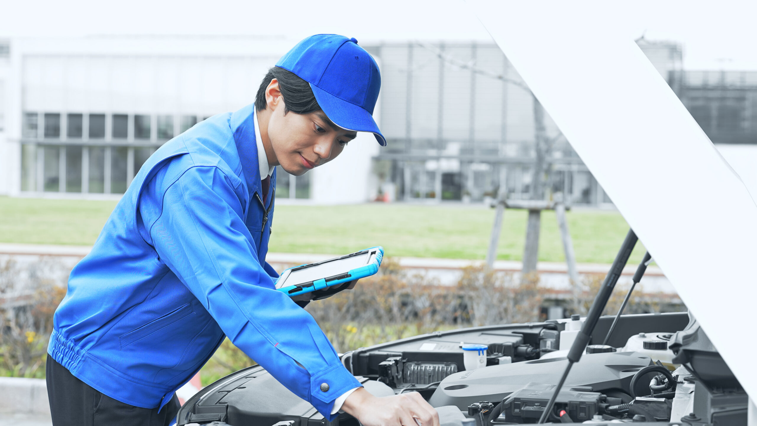 タブレットを使って車を点検する整備士